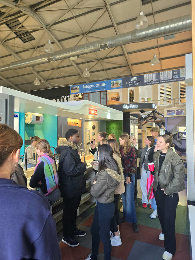 A group of students gathered at a tap and basin display in the exhibition hall
