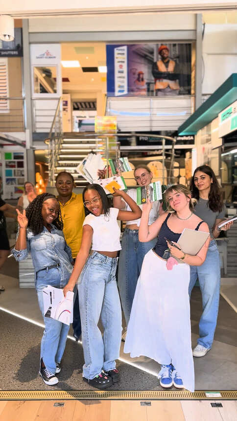 A smiling group of students holding up the product brochures they collected